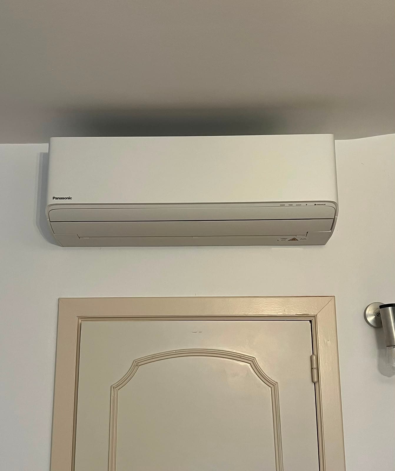 Unité intérieure de climatisation installée au-dessus d’une porte